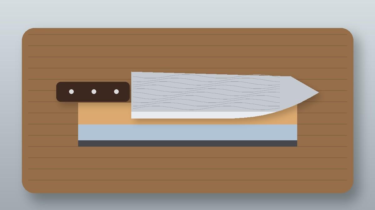 Japanese Damascus chef knife resting on a two-sided whetstone